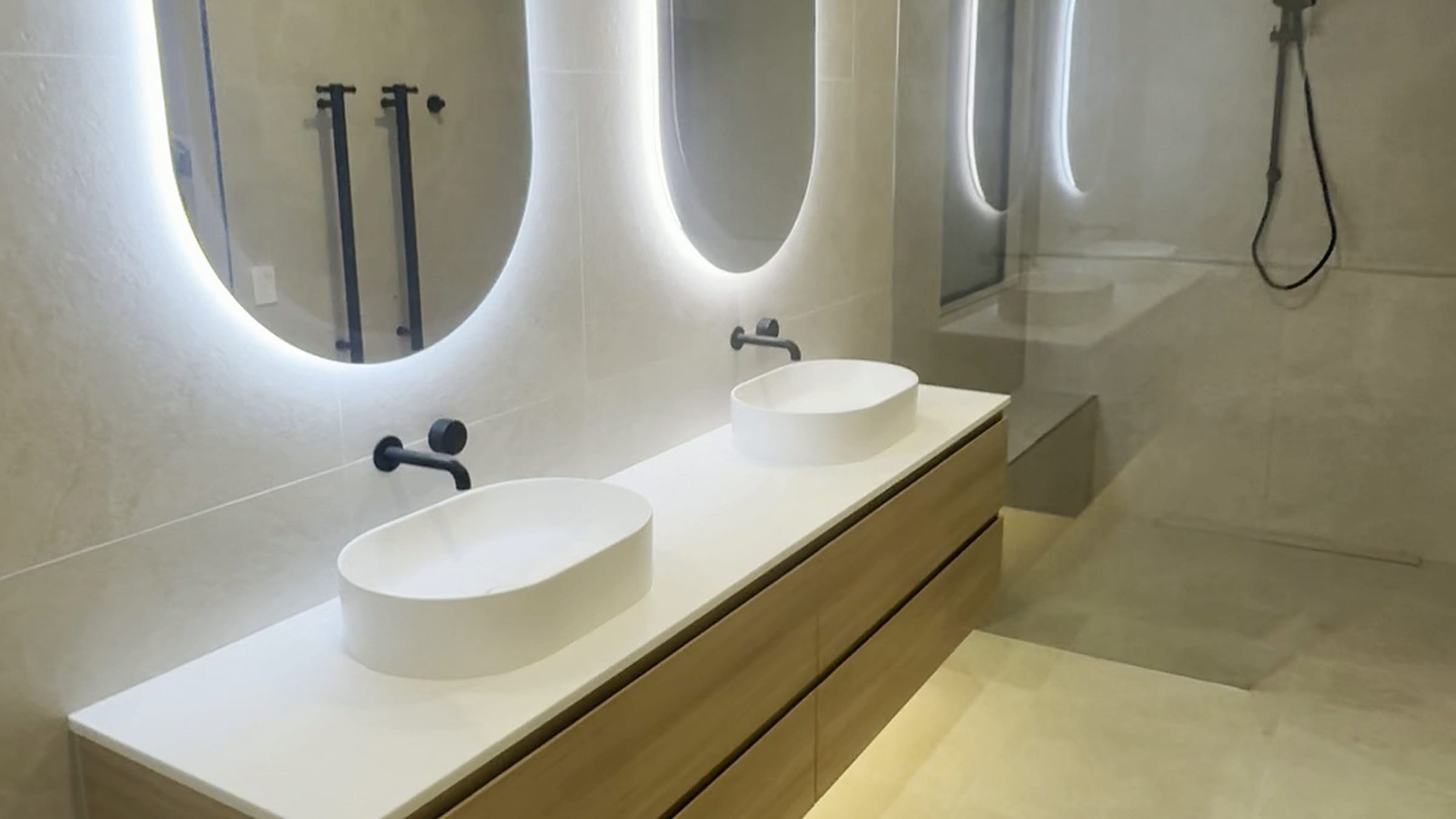 Renovated bathroom with a double floating vanity and backlit mirrors