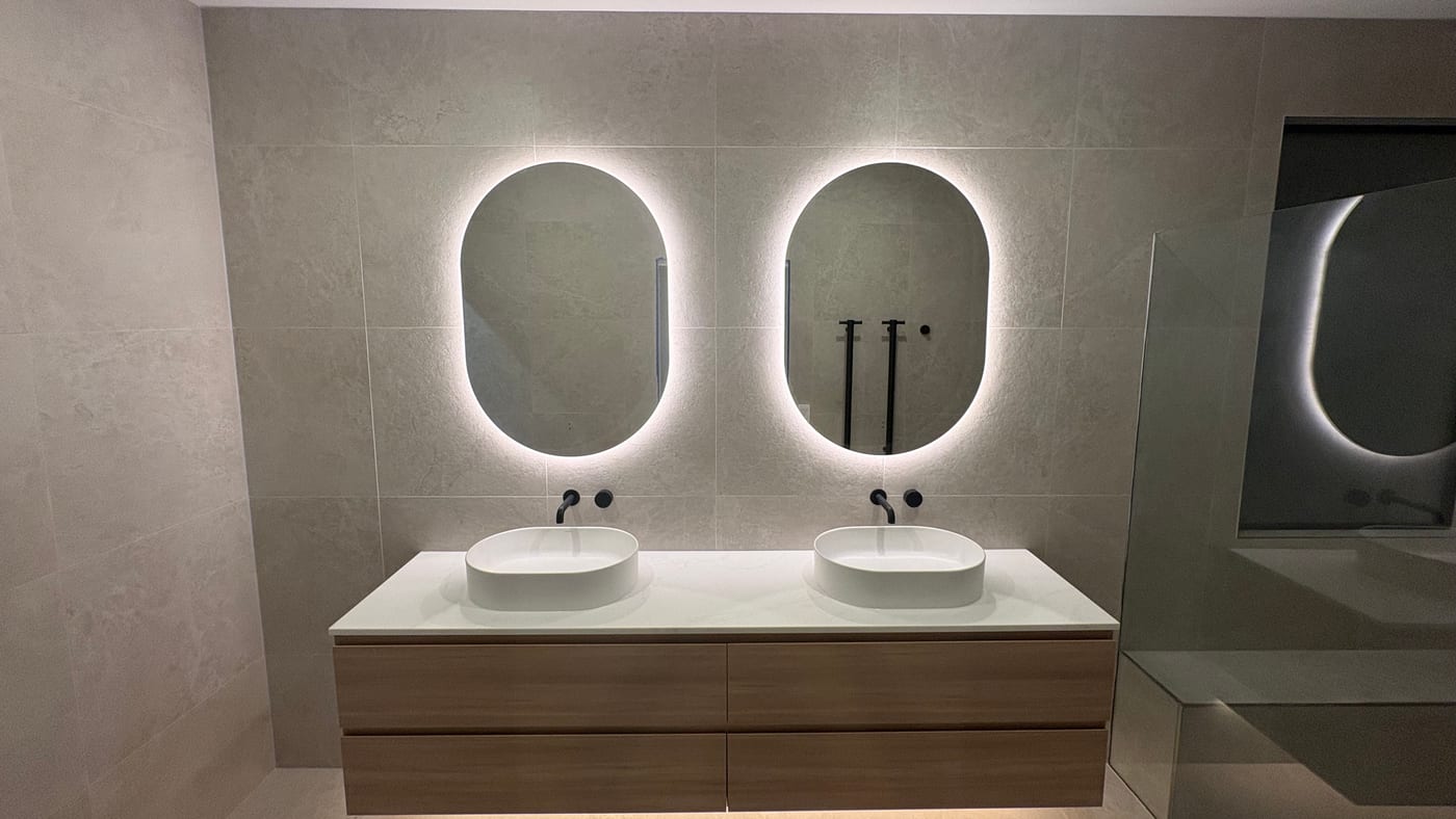 Renovated bathroom with a double floating vanity and twin backlit mirrors