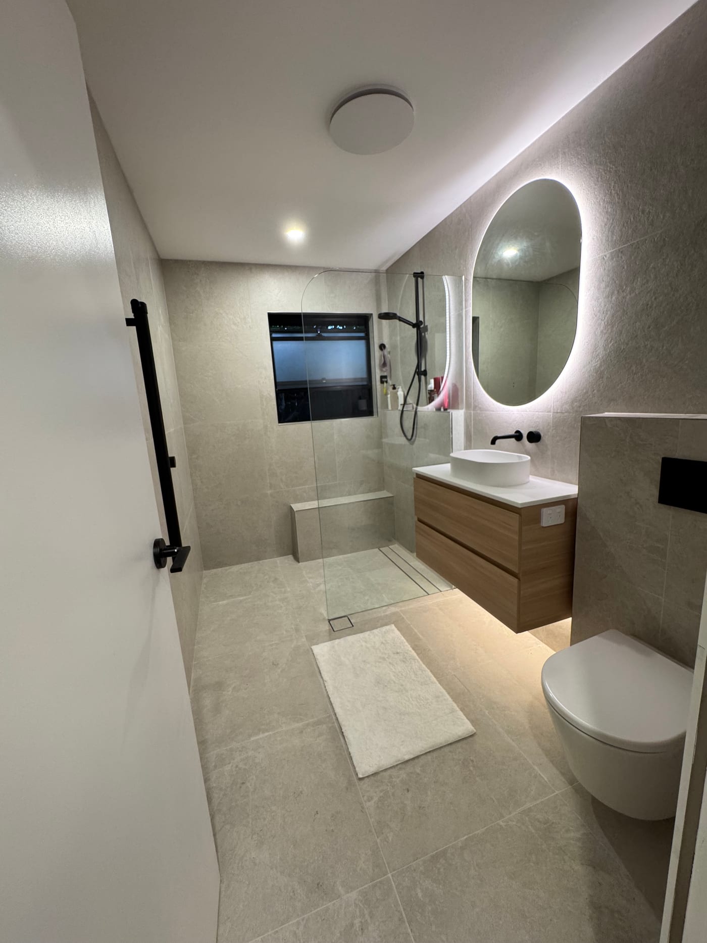 Bathroom renovation with a walk-in shower, wall-hung vanity and backlit mirror