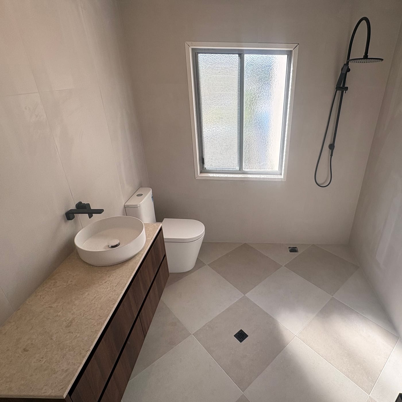 Bathroom renovation with a stone-top vanity, rail shower and tiled floor